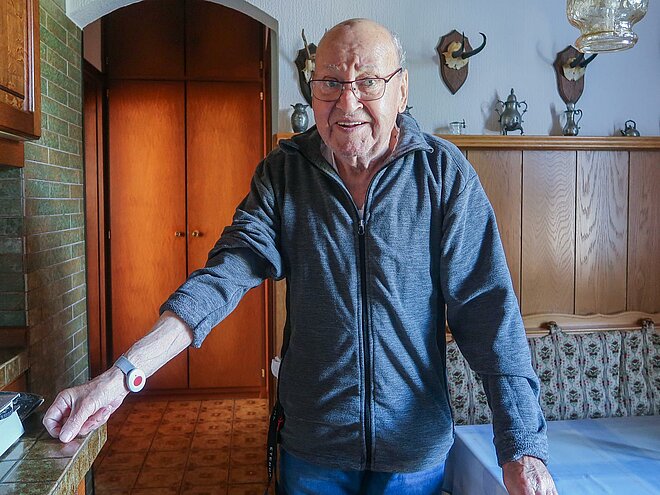 Herbert Höss ist 83 Jahre, ein gut gelaunter Rentner, und er trägt ein Armband mit rotem Knopf am Handgelenk.